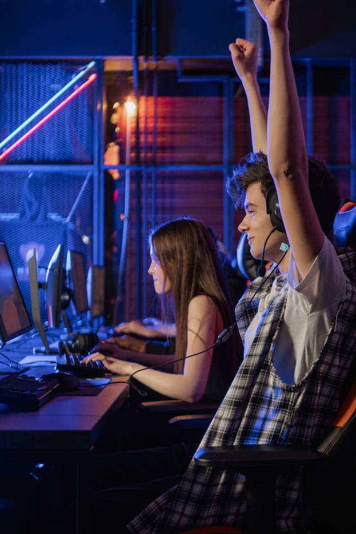 Young gamers celebrating a victory in a video game competition at an indoor gaming center.